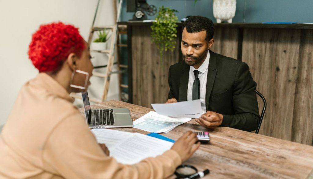 Un expert-comptable et un entrepreneur examinent des documents comptables autour d'un bureau lors d'un premier rendez-vous